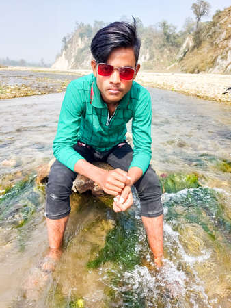Parsa, Narayani Nepal - 16 march 2021: Handsome model man wearing colorful t-shirt with river  mountain beautiful backgroundのeditorial素材