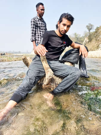 Parsa, Narayani Nepal - 16 march 2021: Handsome model man wearing colorful t-shirt with river  mountain beautiful backgroundのeditorial素材
