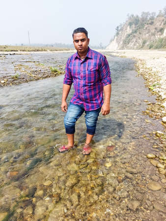 Handsome model man wearing colorful t-shirt with kosi river mountain beautiful backgroundの写真素材