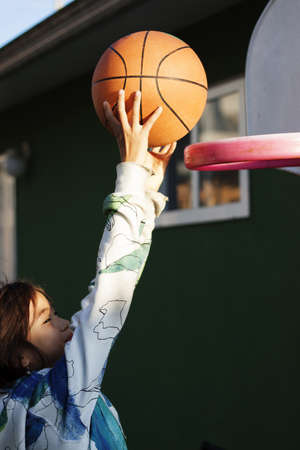 girl slam dunks basketball in backyard