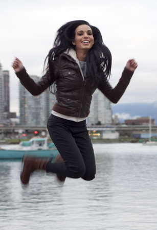 woman jumping into air by waterfront