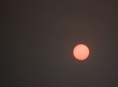 an apocalyptic sun in a dismally smoky gray sky
