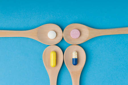 Capsules in a wooden spoons. Flat lay, top view. multi-colored tablets in a wooden spoons on a blue background.の写真素材