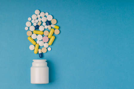 medical pills and tablets spilling out of a white drug bottle. Copy space for text. Closeup,...