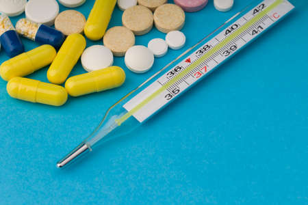 Many different pills, medical thermometer, traditional medicine for treating colds, flu, heat on a...