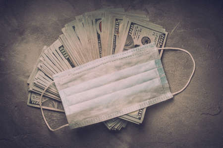 Medical face masks and money. Pneumonia, coronavirus. dramatic light