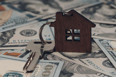 House key on a house shaped keychain and dollar bills