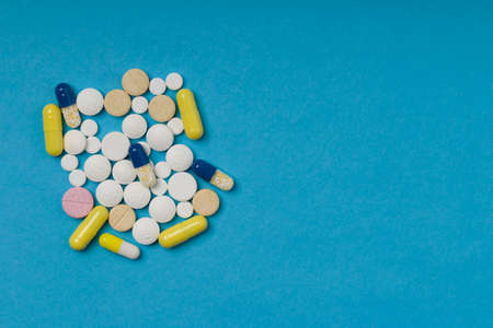 different color pills on blue background. Drugs and medicines concept. Copy space