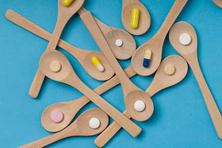 Medical background. Wooden spoon with pills or capsules.の写真素材