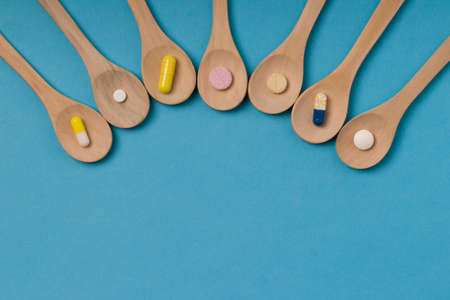 Wooden spoon with pills or capsules. Blue background. Copy spaceの写真素材