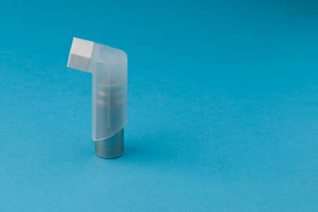 white Asthma inhaler on blue background. close up, copy space