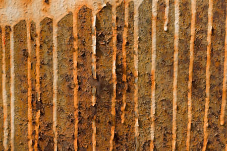 Old metal wall with gray peeling paint and stains of yellow rust and dirt. background texture