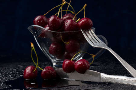 cherries in bowl on the table. Water drops. dark blue backgroundの写真素材