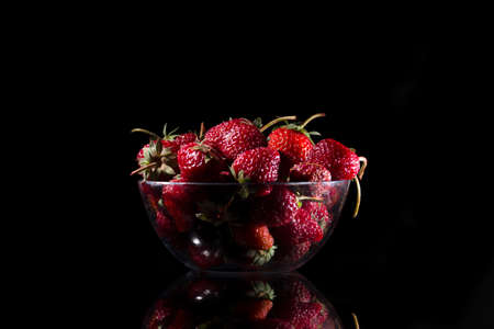 Many strawberry in the glass bowl. Black backgroundの写真素材