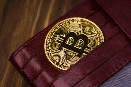 Bitcoin gold coin in leather wallet, close-up. concept of virtual cryptocurrencyの写真素材