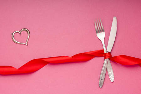 cutlery in red ribbon and heart on a pink background. valentine day conceptの写真素材