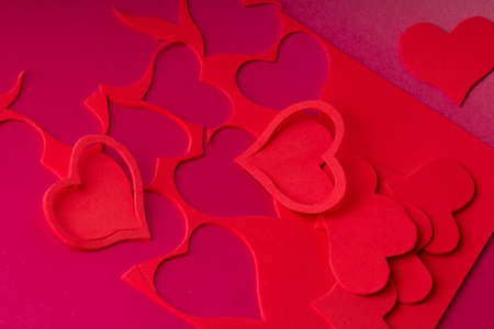Decorative element in the form of a heart lies on the background of red paper with carved hearts.の写真素材