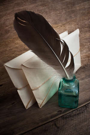 Postage on the background of an old wooden board with a pen for writing in the ink の写真素材