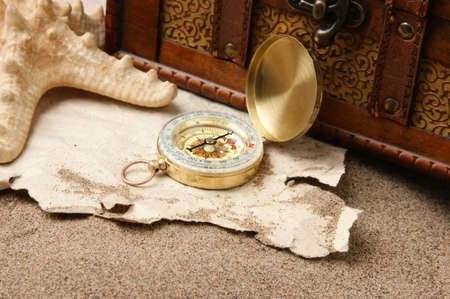 Compass on old sheet crumpled paper against the background of sandの写真素材