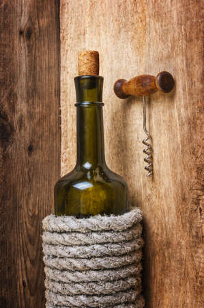 bottle of wine wrapped with rope on the background of the old wooden planksの写真素材