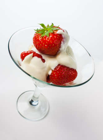Strawberries with whipped cream and mint leaf in a glass on a white backgroundの写真素材