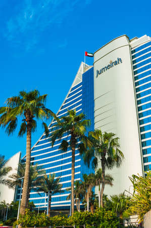 DUBAI, UAE - November 15: Palm trees waving in the wind and giant chess board in front of Jumeirah Beach Hotel, wave-shaped luxury resort, well-known Dubai landmark, on November 15, 2012, Dubai, UAE.のeditorial素材