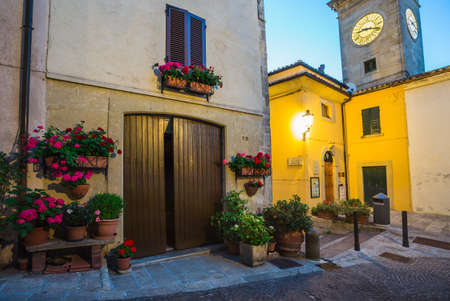 Door in an old house decorated with flower pots and flowers at night