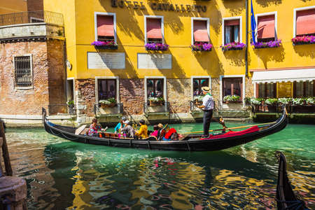 VENICE, ITALY - JUNE 26: Tourists travel on gondolas at canal on June 26, 2014 in Venice, Italy . Gondola trip is the most popular touristic activity in Venice.のeditorial素材