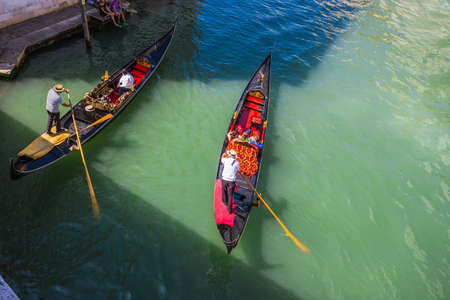 VENICE, ITALY - JUNE 26: Tourists travel on gondolas at canal on June 26, 2014 in Venice, Italy . Gondola trip is the most popular touristic activity in Venice.のeditorial素材