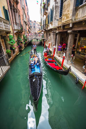 VENICE, ITALY - JUNE 26: Tourists travel on gondolas at canal on June 26, 2014 in Venice, Italy . Gondola trip is the most popular touristic activity in Venice.のeditorial素材