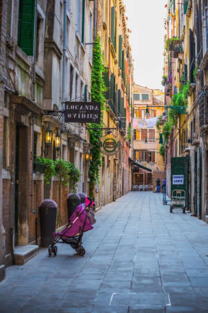 Narrow canal among old colorful brick houses in Venice, Italy.のeditorial素材