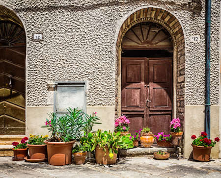 ITALY - JUNE 22, 2014: Windows and doors in an old house decorated with flower pots and flowersのeditorial素材