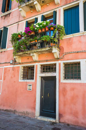 ITALY - JUNE 26, 2014: Windows and doors in an old house decorated with flower pots and flowersのeditorial素材
