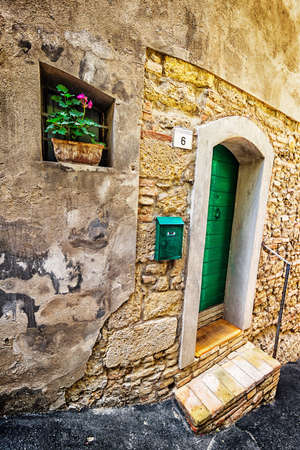 ITALY - JUNE 23, 2014: Windows and doors in an old house decorated with flower pots and flowersのeditorial素材