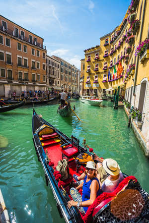 VENICE, ITALY - JUNE 26: Tourists travel on gondolas at canal on June 26, 2014 in Venice, Italy . Gondola trip is the most popular touristic activity in Venice.のeditorial素材
