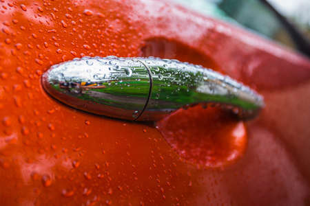 Handle orange car is wet from the rainの写真素材