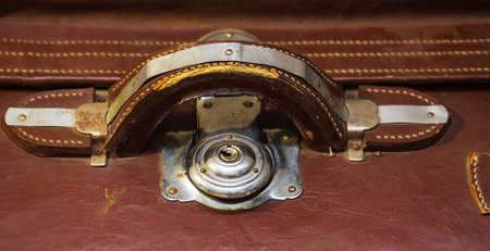 Front view of vintage worn-out leather suitcase with three metallic locks in retro style.の写真素材