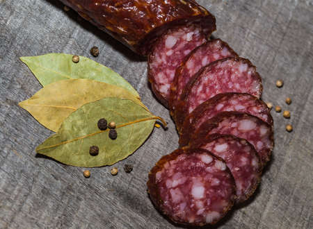 sliced smoked sausage on the wood background with spicesの写真素材