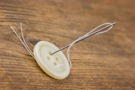 Buttons with needle and thread on the boardの写真素材