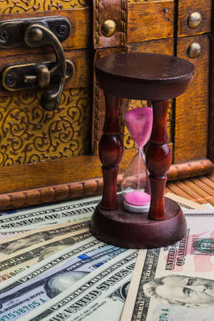 Time is money. An hourglass on the background of money