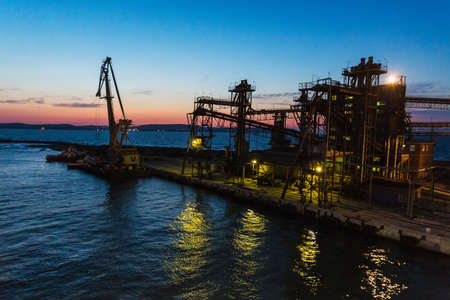 Panorama image of the illuminated cargo port in Crimea at night with container terminals, cargo ships and cranesの写真素材