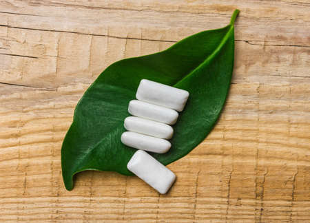 chewing gum is on a leaf on the background of wooden boardsの写真素材