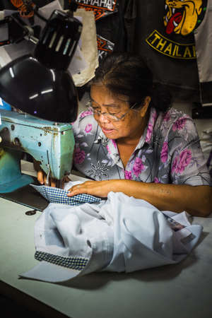 PATTAYA, THAILAND - APRIL 4, 2015: Old woman sews on the sewing machine in the streetのeditorial素材