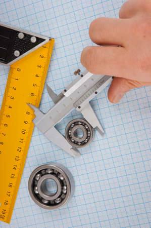 calipers, bearing and square on the background of graph paper