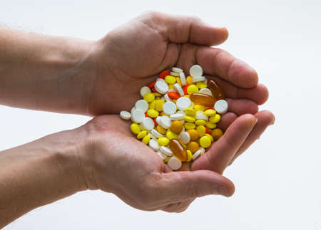 handful of pills in his hands on white backgroundの写真素材