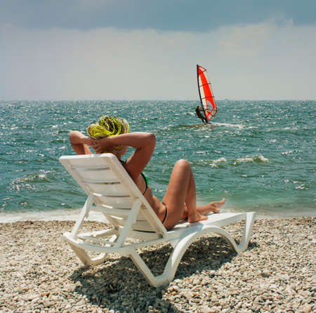 girl on the white chaise lounge on the beach in sunny dayの写真素材