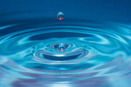 Water drop falling into water making a perfect concentric circlesの写真素材