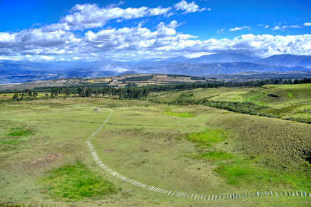 High view of the Cochasqui pyramid museum, with a walkway, on a sunny and cloudy day. Cochasqui, Pichincha Province, Ecuador.の写真素材