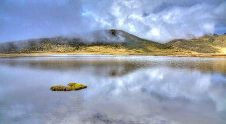 Lake Limpiopungo, in the Cotopaxi National Park, on a foggy and cloudy morning, reflecting the sky and mountains. Ecuador.の写真素材