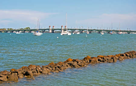 Wave breaker made of stones with the bridge of lions in the background, at Saint Augustine's bay